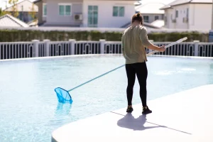 young_man_professional_cleaner_worker_cleaning_pool_with_scoop_net